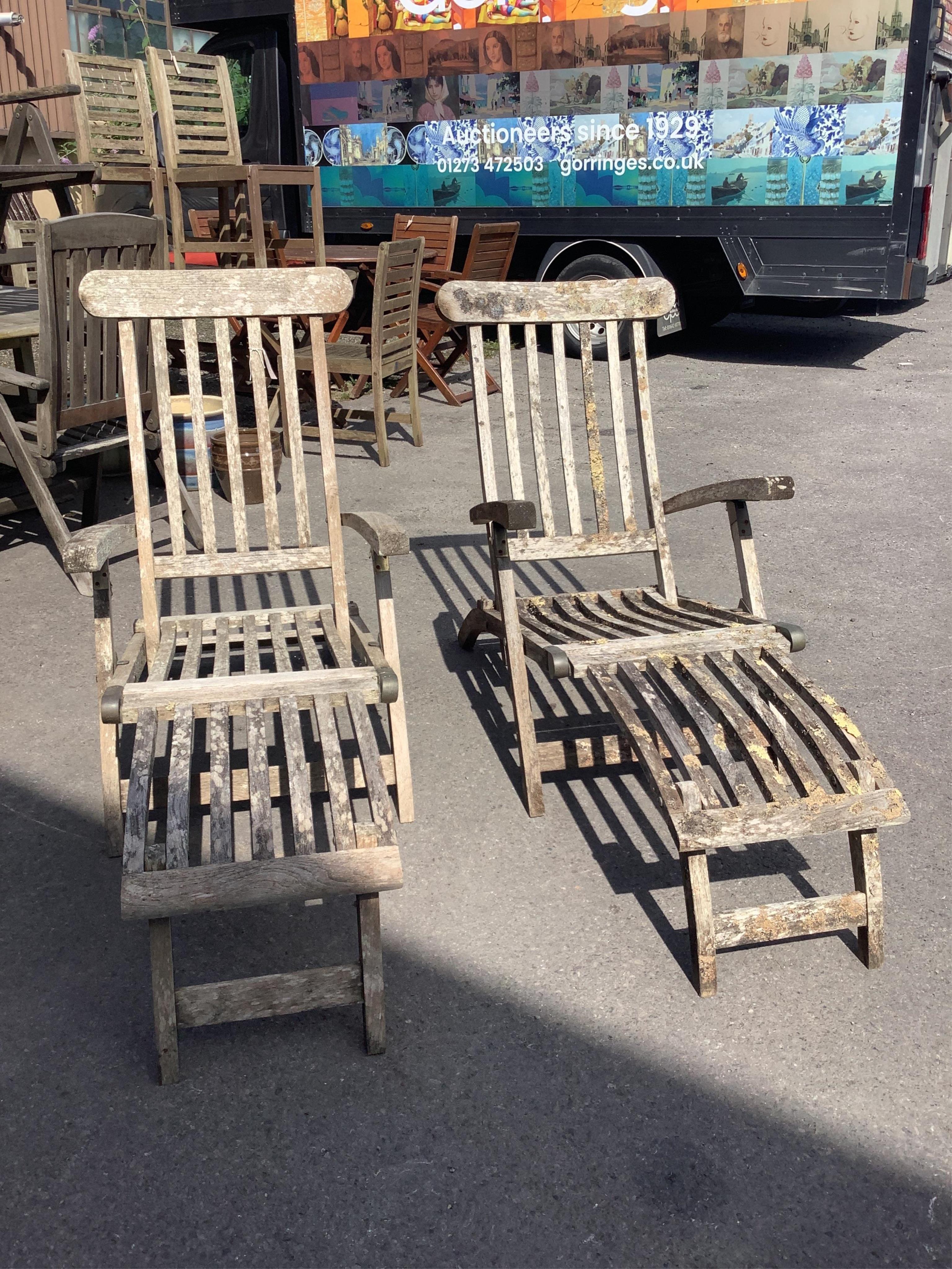A pair of weathered teak steamer garden chairs, width 59cm, height 98cm. Condition - fair
